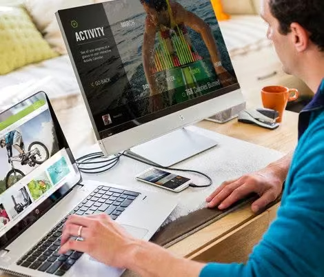 A man using a desktop and a laptop