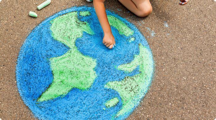 A child drawing planet Earth on the ground